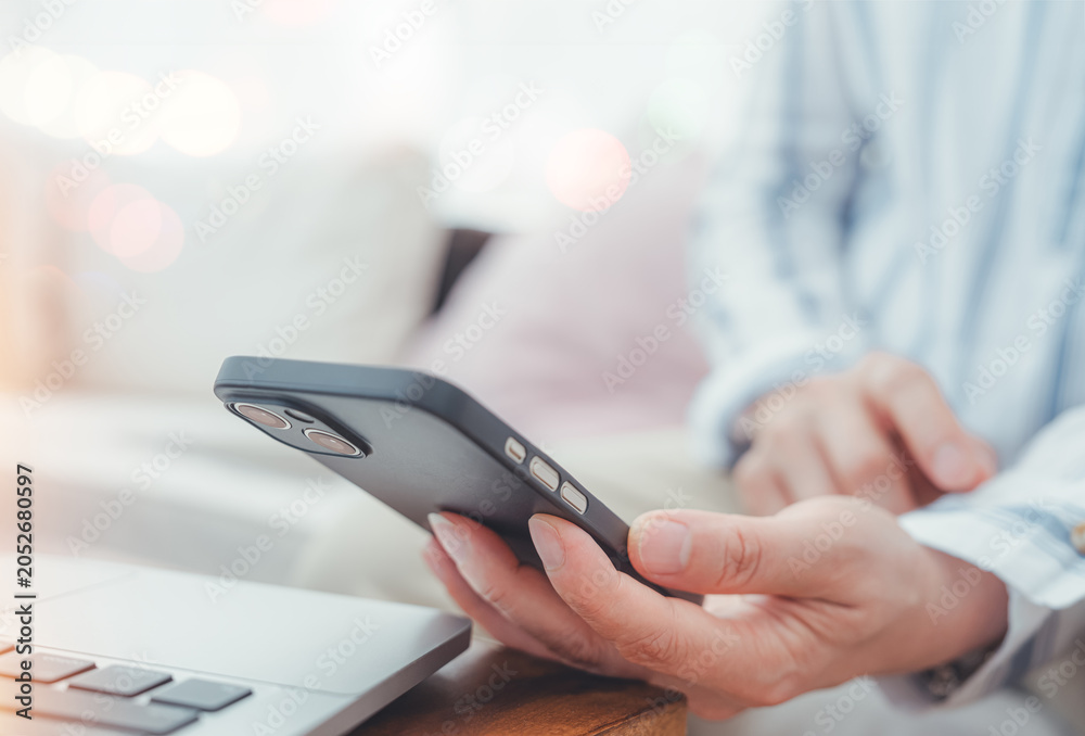 Fototapeta premium Person using smartphone beside laptop for email communication, Business productivity, Online workflow, Mobile connectivity. Digital communication, Remote work, Information access, Technology concept 