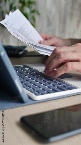 Person reviews financial documents and types on tablet keyboard while completing online application at quiet home workspace