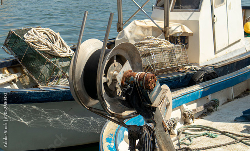 Fotografie Rusty metal winch reel and wire mesh traps on a commercial fishing vessel in a b