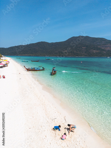 Vertical photo of Mother playing with kids on the beach in a beautiful beach with turquoise water in Koh Lipe Island, Thailand