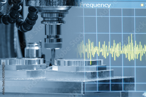 Abstract technology scene of a CNC milling machine cutting aluminum parts layered with a frequency graph background in light blue.