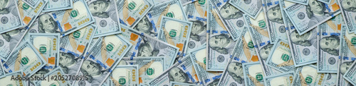 Stacks of bills lie scattered across a surface. Each bill shows distinct design elements and currency markings. Banner