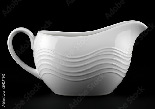A white ceramic gravy boat with wavy lines on a black background
