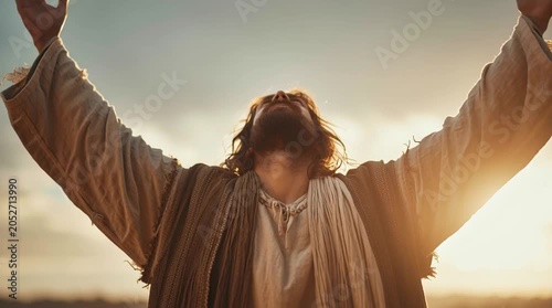 Jesus Christ with open arms looking up to the sky at sunset with warm light