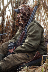 A duck hunter hides in a reed duck blind