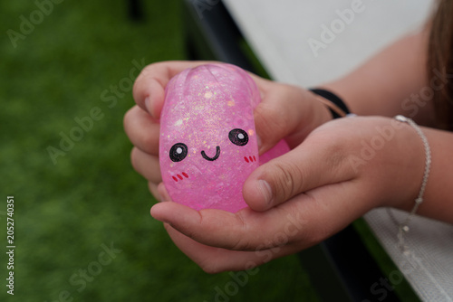 Cuadro en lienzo Close-up of a child squeezing a pink glitter squishy toy with smiling face, high
