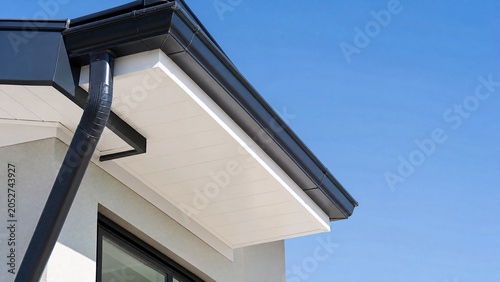 Clean white soffit board under eaves contrasting with dark rain gutter.
