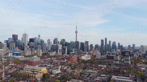 Urban landscape showcasing Toronto's financial district skyline, residential neighborhoods and iconic CN Tower under blue sky, cityscape panorama