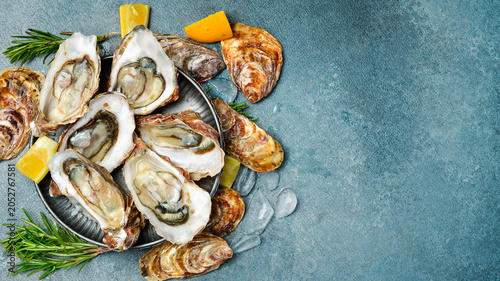 Bild auf Leinwand Fresh oysters with lemon and spices on a metal plate with ice