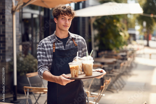 Teenage server delivering refreshing drinks at a café patio, perfect for restaurant marketing, youth employment campaigns, and customer experience content. Selective focus.