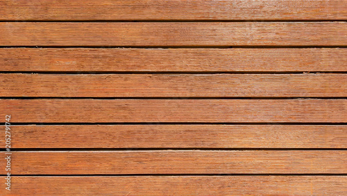 Wood deck planks forming a durable horizontal surface and natural background, showcasing warm brown tones and textured grooves, creating a strong wooden pattern