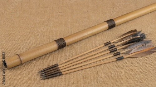 Bamboo blowpipe and feathered wooden darts on jute cloth, traditional skill and organic sport concept.