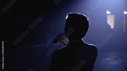 Silhouette of a singer performing on a dark stage