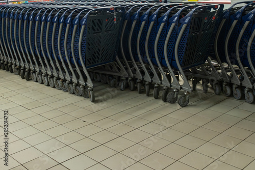 Obraz na plátně Neat rows of empty blue shopping carts stand in a supermarket terminal floor