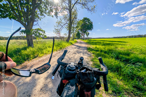 First person view of cycling on a rural road. Handlebar with bags and water