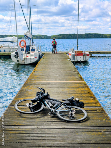 A bicycle lying on a pier next to man cyclist and boats