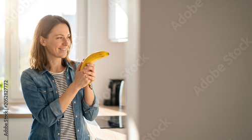 Smiling Woman Holding Banana Like a Toy Gun