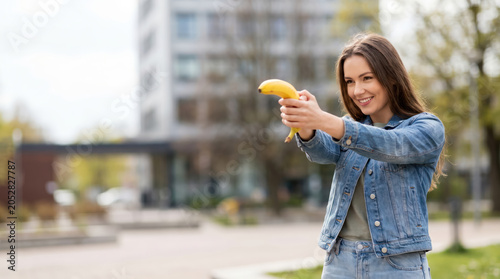 Smiling Woman Holding Banana Like a Toy Gun
