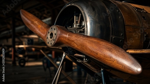 The wooden propeller of a vintage monoplane in a quiet hangar.
