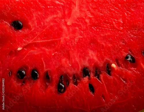 Macro texture of fresh sliced ripe watermelon pulp with black seeds
