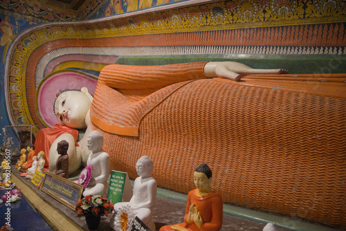 Fényképezés Reclining Buddha statue with small devotional figures inside Kande Viharaya Temple in Aluthgama, Sri Lanka