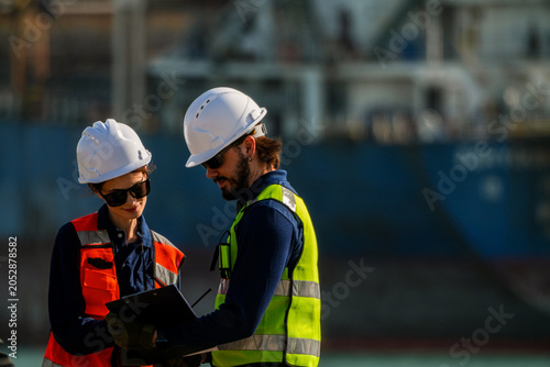Tableau sur toile Engineering team collaborating on technical schematics and vessel maintenance plans at a bustling maritime shipyard facility during the daytime
