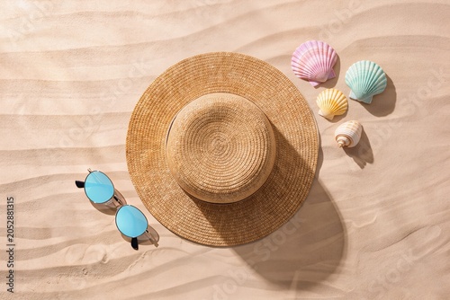 Straw Hat, Sunglasses, Seashells On Sand Creating Relaxed Seaside Packing Scene. Flatlay Arrangement Showcases