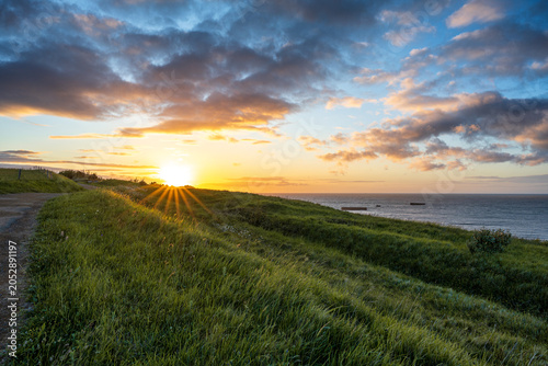 Fotografija Beautiful sunrise over the Normandy coast in Arromanches France with remains of WWII Mulberry Harbour in the sea