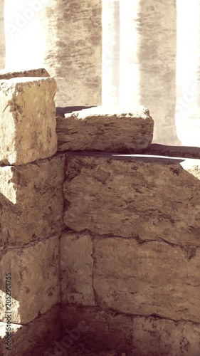 Dust fills the air around weathered stone ruins with tall columns illuminating the past. The setting hints at a longstanding civilizations architectural achievements.