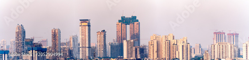 Aerial drone shot showing high rise skyscrapers under construction and completed cityscape of gurgaon delhi noida at dusk with sunlight reflected in India