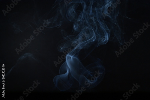 Obraz na plátne Ethereal Swirls of Blue Smoke Against a Dark Background Creating a Mysterious an