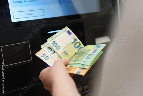 Bild auf Leinwand Customer deposits euro banknotes at an ATM touchscreen banking terminal indoors