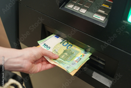 Foto Hand withdraws euro cash from an ATM dispenser during a banking operation