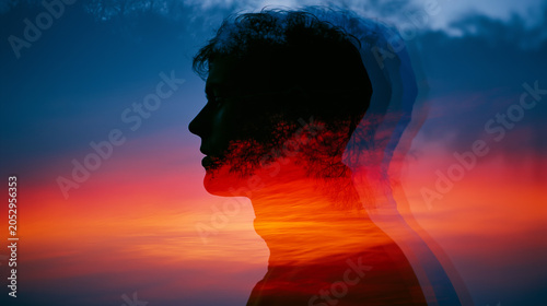 Double exposure silhouette of a man's profile blended with tree branches against a vivid sunset sky