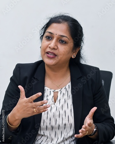 South Asian businesswoman speaking in corporate office interview about equality and inclusion, middle aged corporate worker