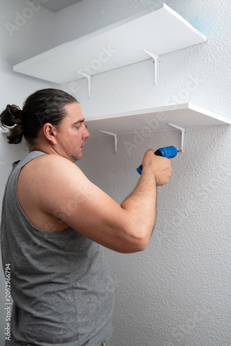 Obraz na płótnie Man installing shelves with power drill for home improvement