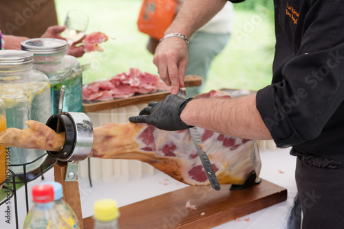 Découpe de jambon cru lors d’un événement gastronomique – artisan charcutier en action