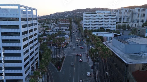 Cinematic high angle establishing shot of traffic on LA streets, cars and palm trees in wealthy Los Angeles neighborhood at sunset