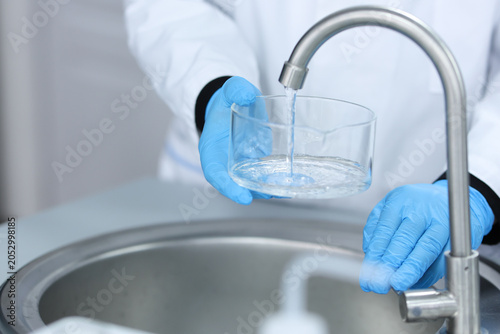 cleaning scientific glassware under running water. Laboratory safety, hygiene and quality control procedures in chemistry research and healthcare testing environment. High quality photo