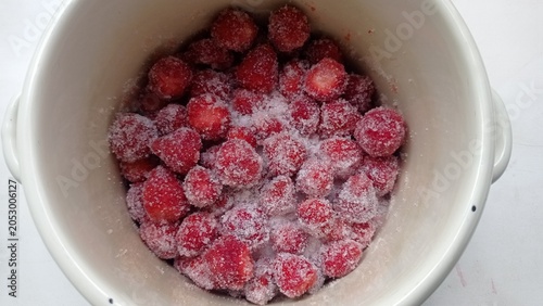 Peeled strawberries are covered with sugar in a saucepan.