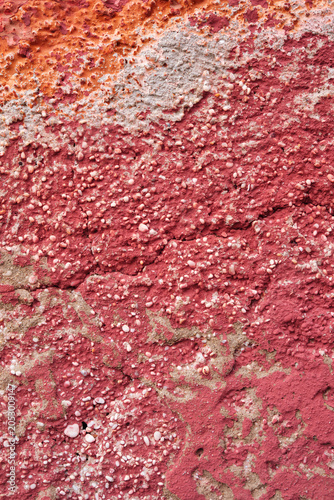 détail de texture sur un mur décrépi de la façade d'une vielle maison en béton et briques rose