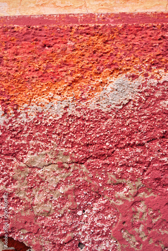 détail de texture sur un mur décrépi de la façade d'une vielle maison en béton et briques rose