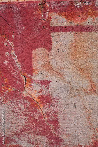 détail de texture sur un mur décrépi de la façade d'une vielle maison en béton et briques rose