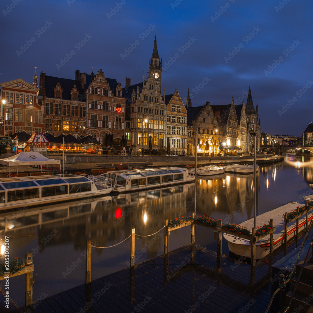 Fototapeta premium Bruges is a museum, Brussels is a meeting, but Ghent is a party! Ghent city centre at night with boats and reflections in the canal river water. 