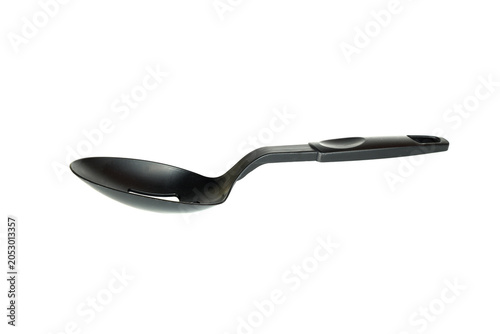 black plastic kitchen spoon with a narrow longitudinal cutout lies horizontally on a white background
