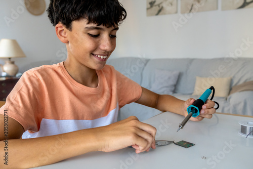Quadro em tela Teen using a tin soldering iron to solder an electrical circuit