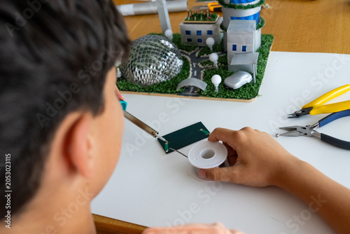 back to school. Teenager using a tin solder to make a project with recycled materials