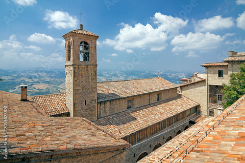 The view of San Francisco church (1351) belfry with dramatic tender cloudy blue sky. San Marino, Italy