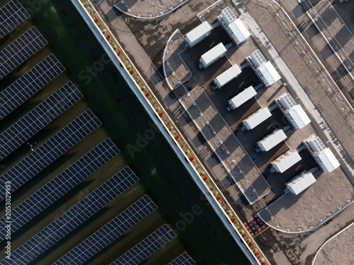 Aerial view of solar photovoltaic panels and energy storage container facilities on a rooftop