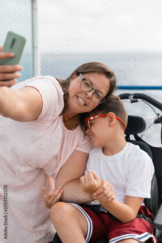Woman and boy with cerebral palsy taking selfie on holidays